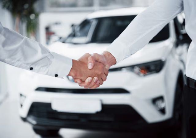 Handshake in front of a white car