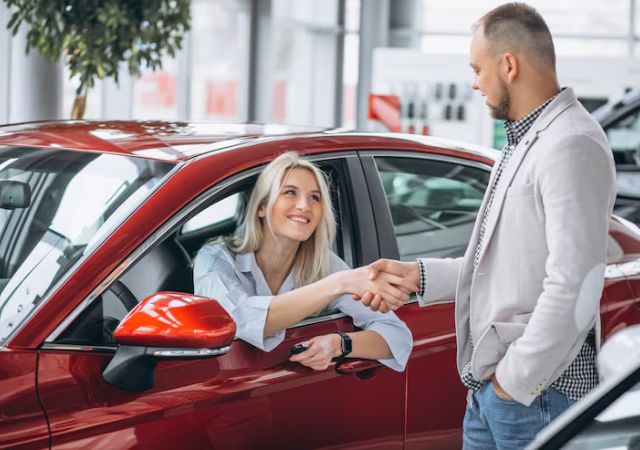 Driver in a red car shaking hands with a salesperson